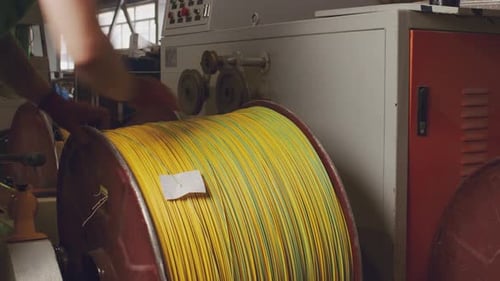 Unrecognizable Worker Rolls a Reel with Cable in Cable Production Plant Close Up