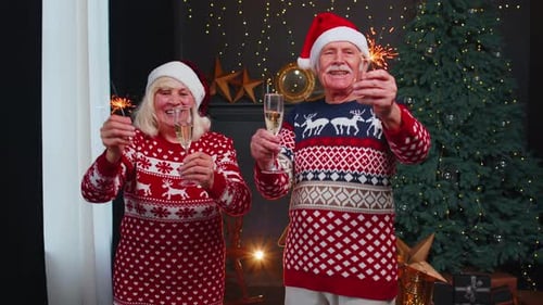 Smiling Senior Grandparents Family Couple Holding Christmas Bengali Sparkles Glasses of Champagne