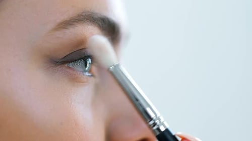 Extreme Close Up Visagiste Applying Eye Shadows Using Cosmetic Brush to Face Teenage Model