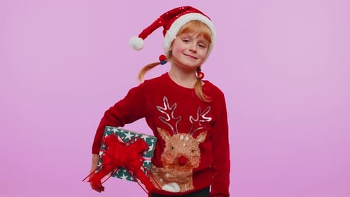 Smiling Child with Christmas Gift Wearing Santa Hat