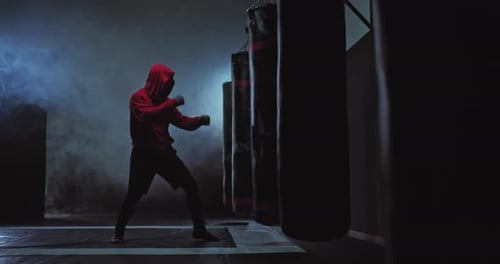Männlicher Boxer schlägt mit seinen Händen auf einen Boxsack, eine Reihe von Schlägen