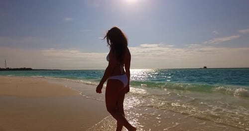 Pretty happy lady relaxing by the sea at the beach on clean white sand and blue background