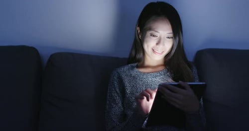Young Woman Using Tablet on Couch at Night