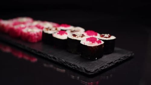 Two different portions of delicious rolls in changing light on a black background. Closeup japanese