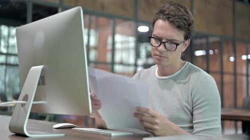 Ambitious Guy Reading Document on Office Desk