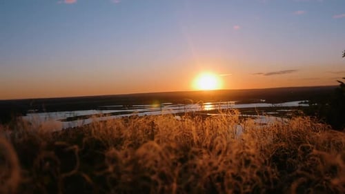 Bright Orange Sunset Over the River and Wheat Field
