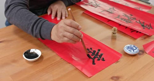 Man write chinese calligraphy for lunar new year, words mean happy new year