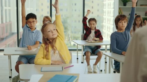 Junior School Students Raise Their Hand in Class to Answer the Teacher's Question