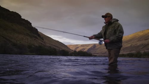 Man fly fishing in beautiful river at sunrise
