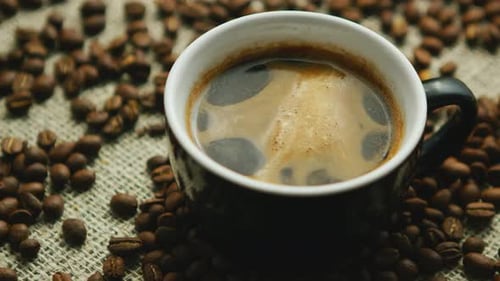 Hot Black Coffee Surrounded by Roasted Coffee Beans