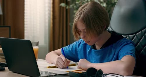 Teen Writing in Notebook at Desk