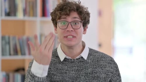 Man Talking and Gesturing in Front of Bookshelf