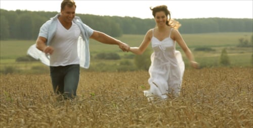 Couple Running Hand-in-Hand Through Wheat Field