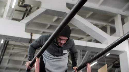 Strong Man Doing Push Up Exercise on Bar in Gym Club