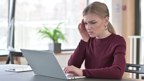 Young Woman with Headache Using Laptop in Office
