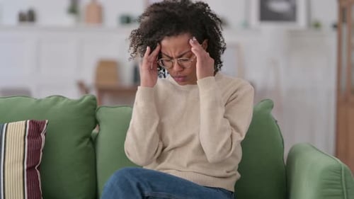African Woman with Headache Sitting on Sofa