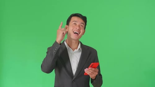 Asian Business Man Use Phone And Thinking Then Raising Her Index Finger In Green Screen Studio