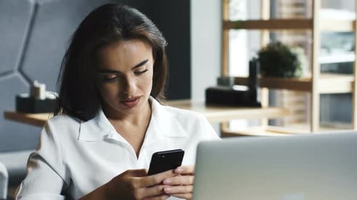 Pretty Young Woman Freelancer Having Break and Scrolling Her Phone at Cafe
