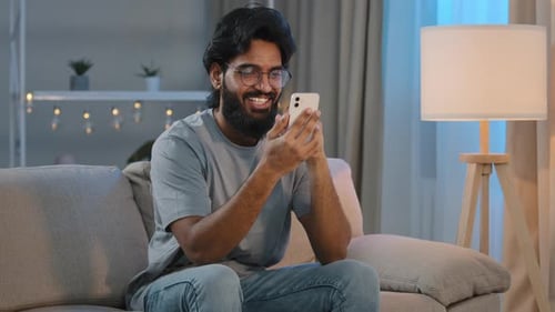 Young Adult Man on Couch Using Smartphone