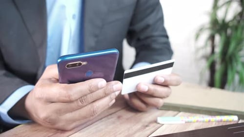 Geschäftsmanhand, die Kreditkarte hält und das Smartphone nutzt, um online einzukaufen