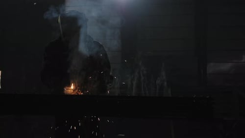 Welder Working in Dark Factory at Night
