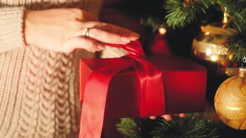 Hands Untying Red Ribbon on Christmas Gift
