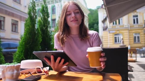 Young Woman Using Tablet Pc in a Cafe on a Summer Terrace