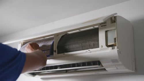 Professional technician male Removing dirty air conditioner filter for wash