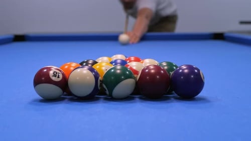 Ein Mann schlägt beim amerikanischen Billard auf die Eier. Sportspiel in Zeitlupe