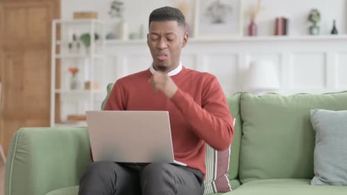 Man Coughing While Using Laptop at Home