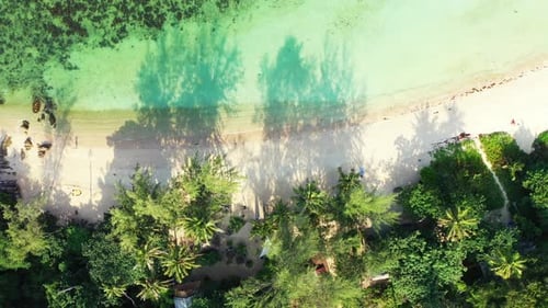 White sandy exotic beach under shadow of palm trees, washed by calm clear water of turquoise lagoon