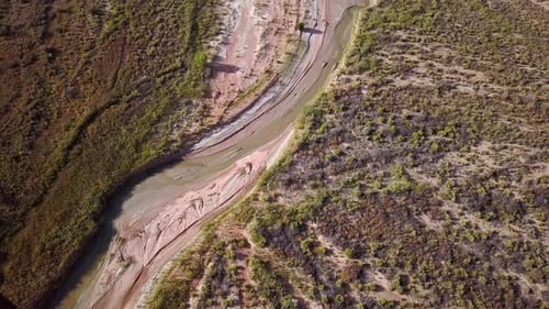 Flying aerial view of winding river flowing through the desert