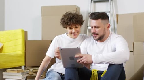 Couple Using Tablet Together After Moving Into New Home