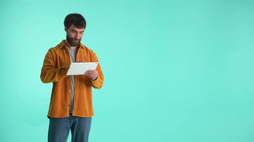 Man Using Tablet Against Solid Blue Background