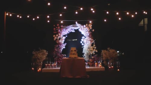 Romantic Wedding Cake Display Under Floral Archway at Night