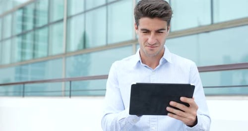 Smiling Man Using Tablet Outside Modern Building
