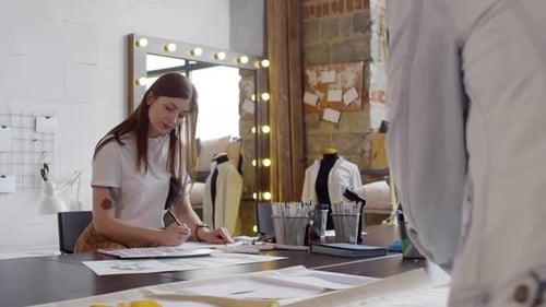 Female Fashion Designer Drawing Sketch in Sewing Workshop