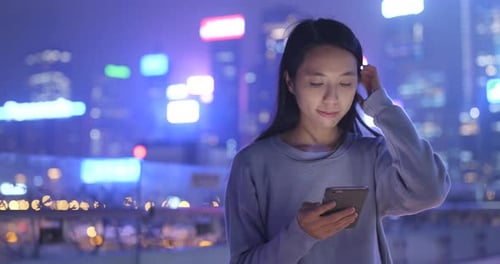 Asian woman use of mobile phone in city at night