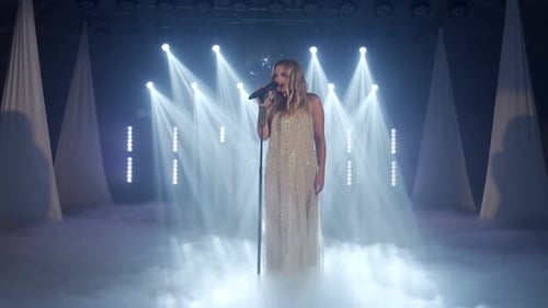 Blonde Woman Sings on Smoky Stage in Gown