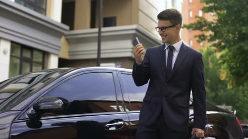 Businessman Talking on Phone Next to Car