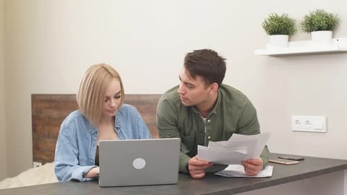 Young Couple Discussing Finances at Home with Laptop