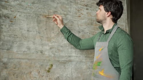 Concentrated Male Artist is Drawing on Easel in His Art Studio Side View