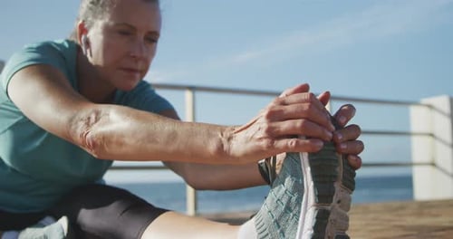 Senior woman stretching her legs on a promenade