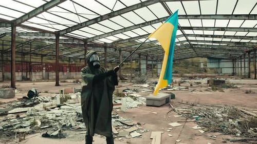 Person in Hazmat Suit Holding Flag in Ruins