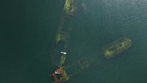 Paddle Boarder Exploring Sunken Ship from Aerial View