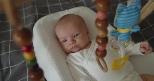 Little Newborn Baby Boy Lies Under Foldable Wooden Montessori Fitness Baby Gym