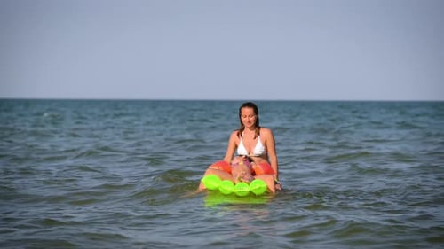 Woman and Child Relaxing on Raft in Ocean