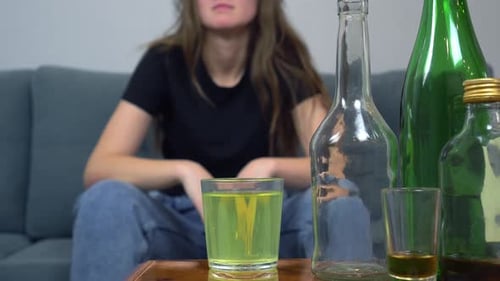 Young Woman Sits With Empty Bottles