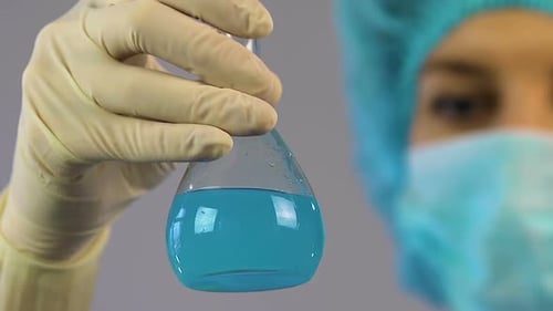 Medical Researcher Holding Tube With Blue Liquid in Hand, Conducting Research