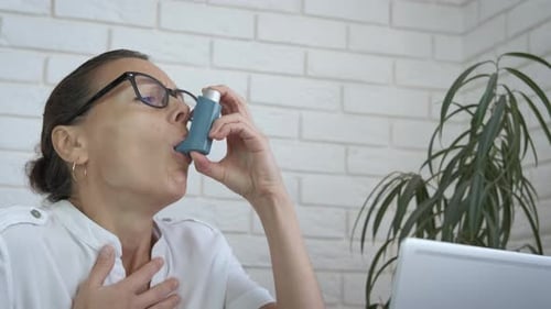 Woman Using Inhaler During Asthma Attack Indoors